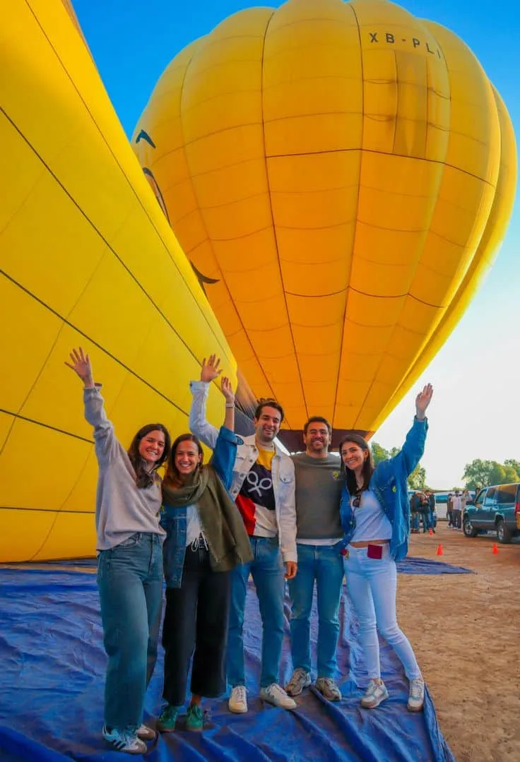 Grupo de pasajeros frente a globo aerostático emoji en Teotihuacán